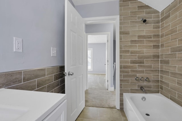 bathroom featuring tile patterned flooring, tiled shower / bath combo, and tile walls