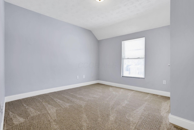 carpeted empty room with vaulted ceiling