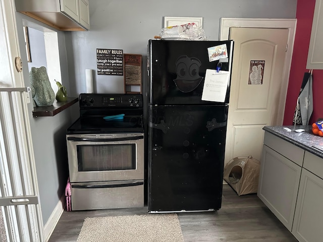 kitchen featuring hardwood / wood-style floors, black refrigerator, and stainless steel electric range