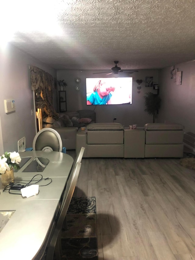 dining area featuring hardwood / wood-style flooring, ceiling fan, and a textured ceiling