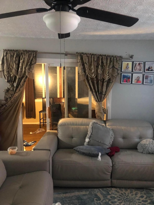 living room featuring ceiling fan, hardwood / wood-style floors, and a textured ceiling