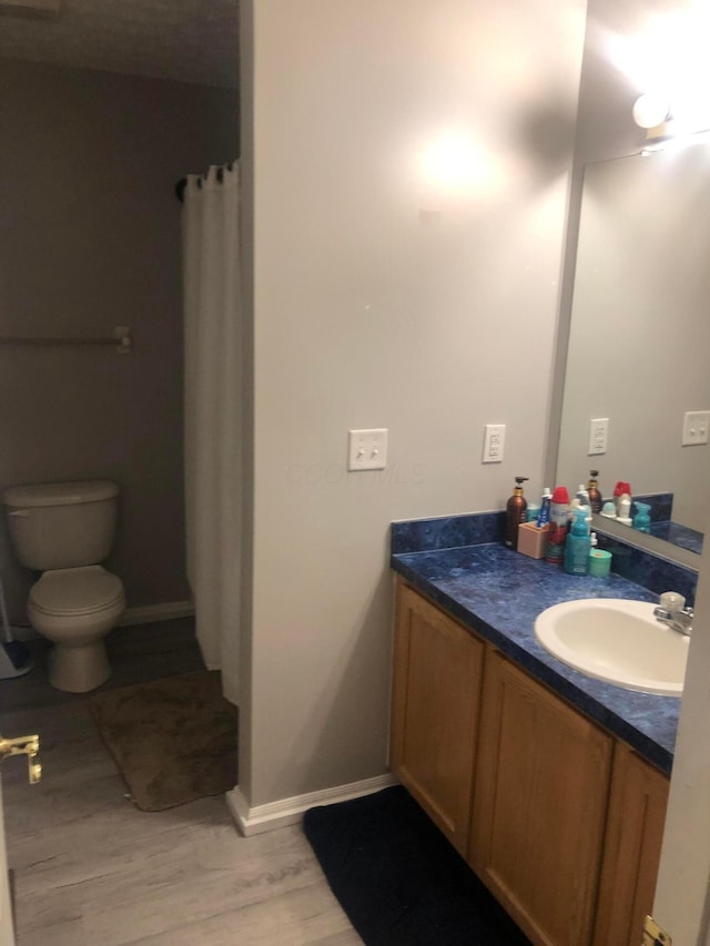 bathroom featuring vanity, hardwood / wood-style flooring, curtained shower, and toilet