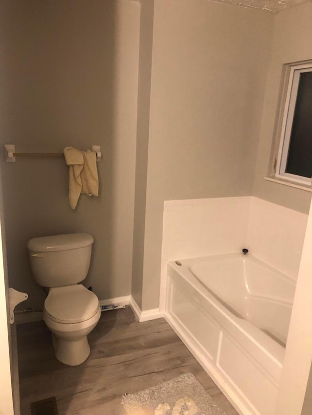 bathroom featuring toilet, hardwood / wood-style floors, and a tub