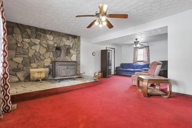 living room with ceiling fan, carpet, a textured ceiling, and a wood stove