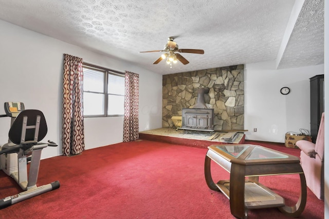 carpeted living room featuring ceiling fan, a textured ceiling, and a wood stove