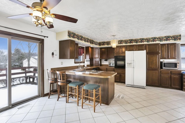 kitchen with a breakfast bar, black oven, white fridge with ice dispenser, kitchen peninsula, and a textured ceiling