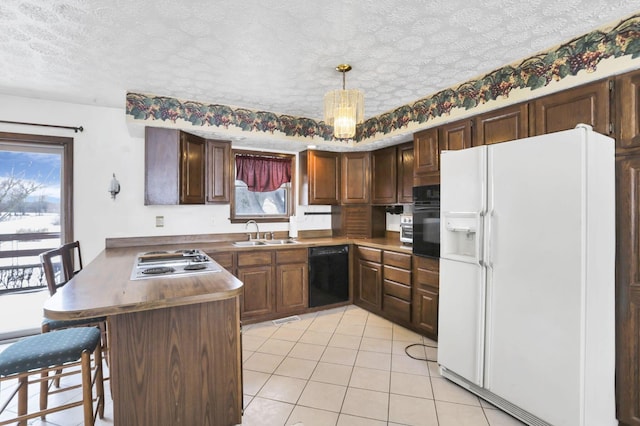 kitchen with a breakfast bar, decorative light fixtures, black appliances, sink, and kitchen peninsula