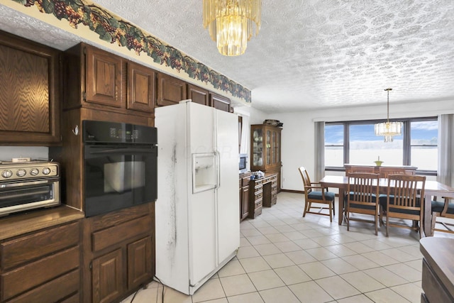 kitchen with an inviting chandelier, decorative light fixtures, light tile patterned floors, black oven, and white refrigerator with ice dispenser