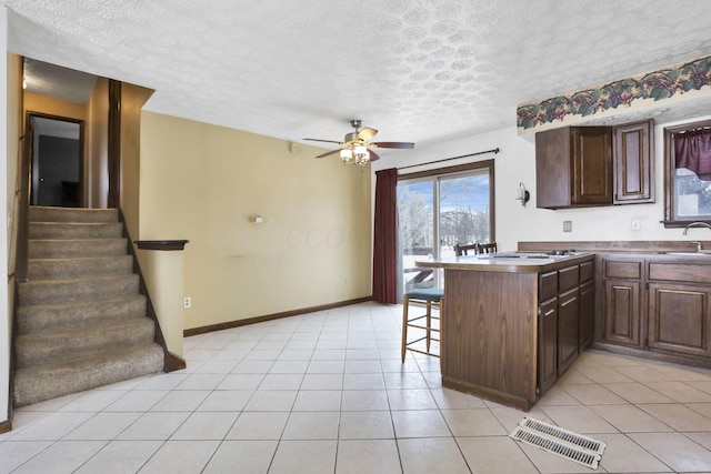 kitchen featuring a breakfast bar, kitchen peninsula, sink, and light tile patterned floors