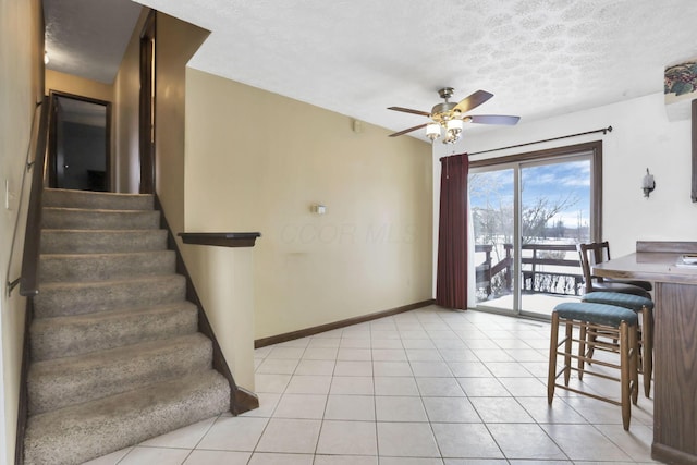 interior space with ceiling fan, a textured ceiling, and light tile patterned floors