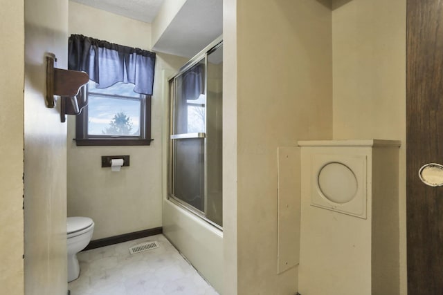 bathroom featuring enclosed tub / shower combo and toilet