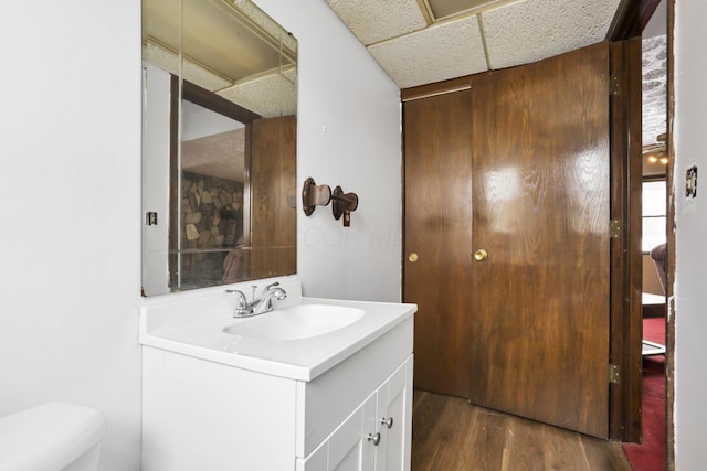 bathroom featuring a paneled ceiling, vanity, toilet, and wood-type flooring