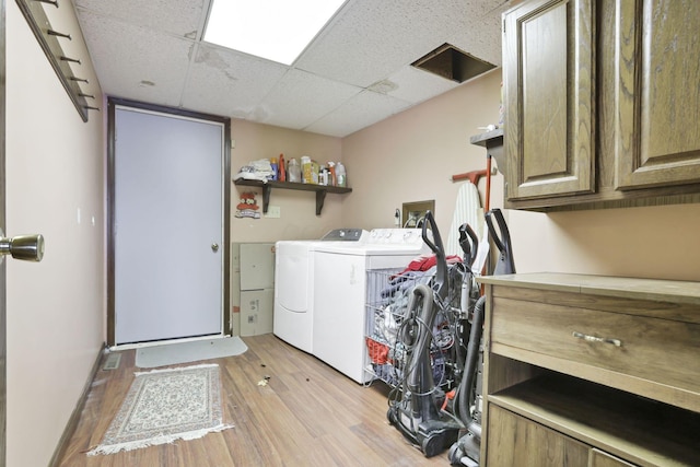 washroom featuring washer and dryer, cabinets, and light wood-type flooring