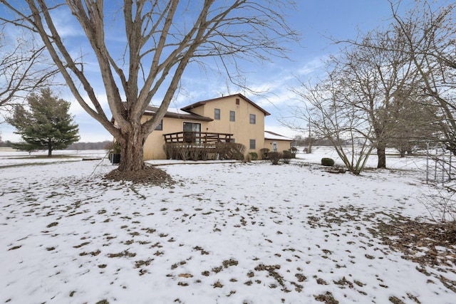 snow covered back of property with a deck