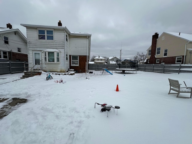 snow covered house featuring a trampoline