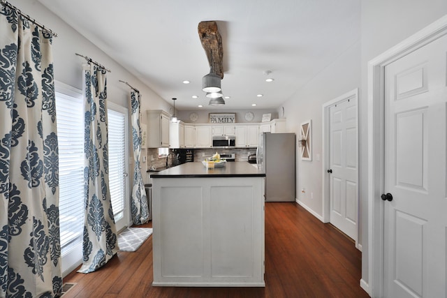 kitchen featuring stainless steel appliances, decorative light fixtures, white cabinets, decorative backsplash, and dark wood-type flooring