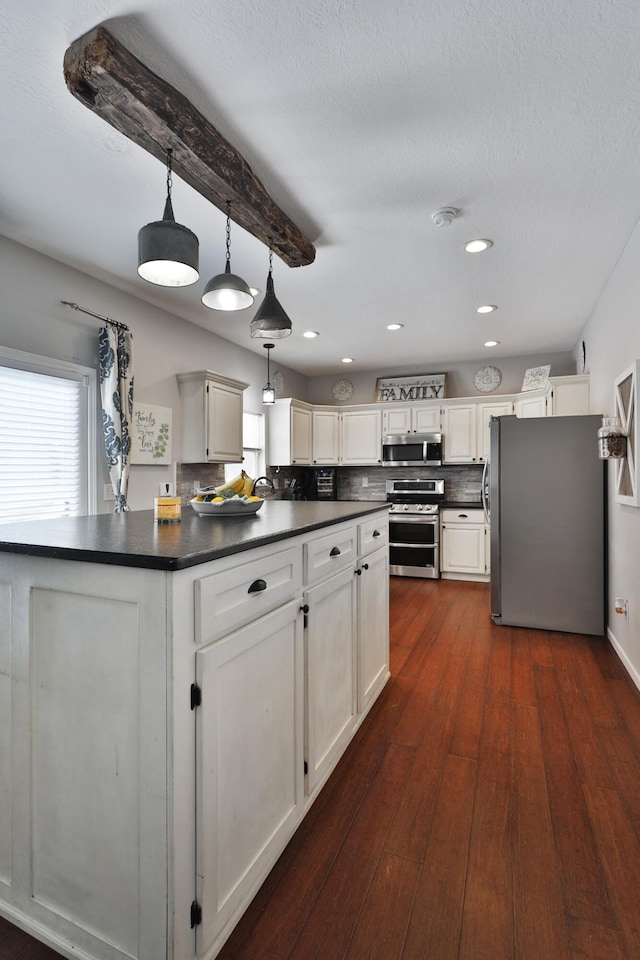 kitchen with appliances with stainless steel finishes, hanging light fixtures, and white cabinets