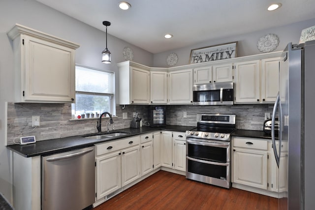 kitchen with stainless steel appliances, white cabinetry, backsplash, and sink