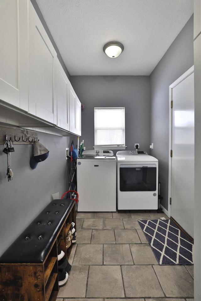 washroom featuring a textured ceiling, cabinets, and washing machine and dryer