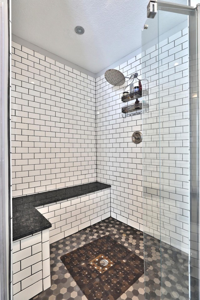 bathroom with a textured ceiling and a shower with shower door