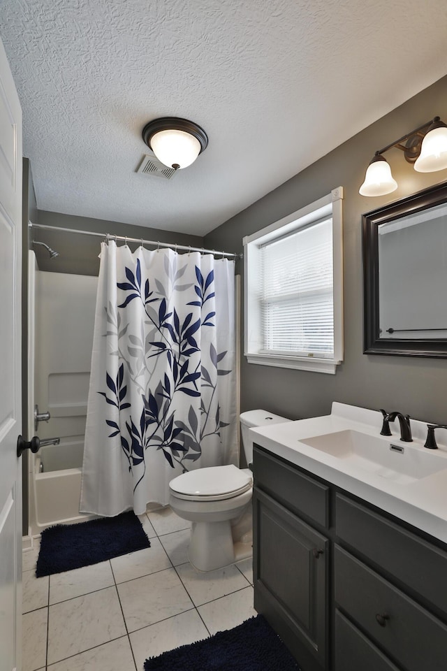 full bathroom featuring tile patterned flooring, toilet, shower / bath combo with shower curtain, vanity, and a textured ceiling