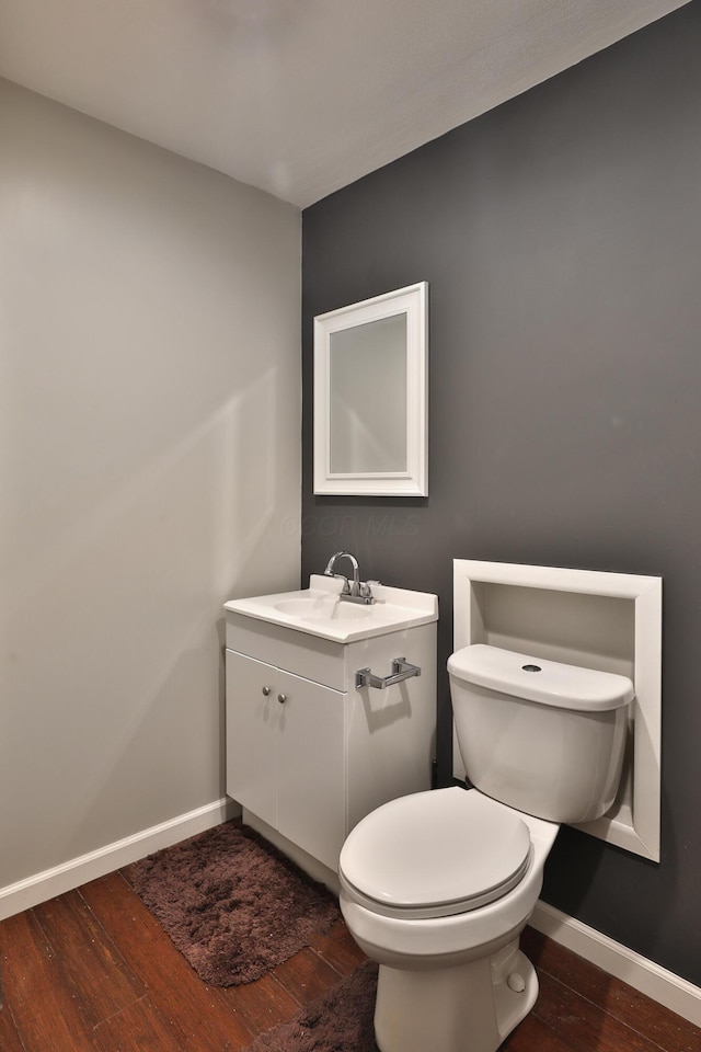 bathroom with toilet, vanity, and hardwood / wood-style floors