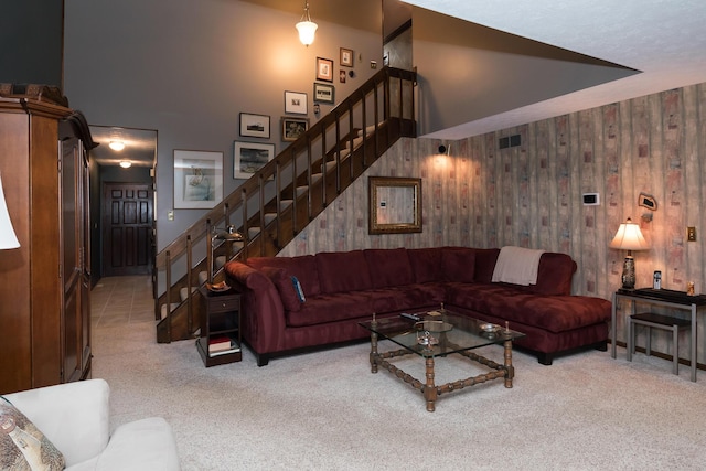 living room with light colored carpet, a towering ceiling, and wooden walls