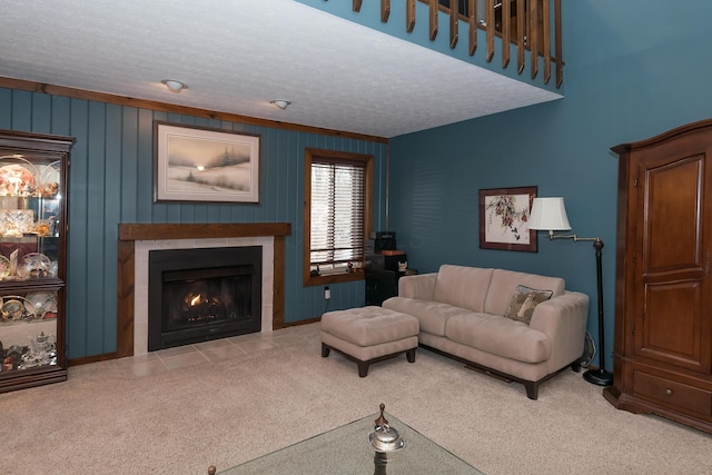 living room featuring a textured ceiling, wood walls, a tiled fireplace, and carpet flooring