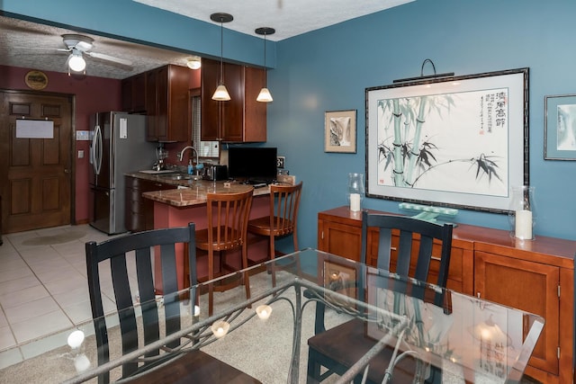 kitchen with a breakfast bar, stainless steel refrigerator, a textured ceiling, and pendant lighting