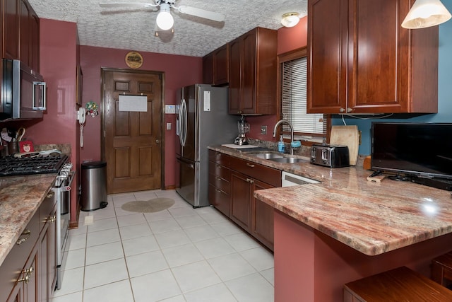 kitchen with pendant lighting, light tile patterned flooring, sink, stainless steel appliances, and a textured ceiling