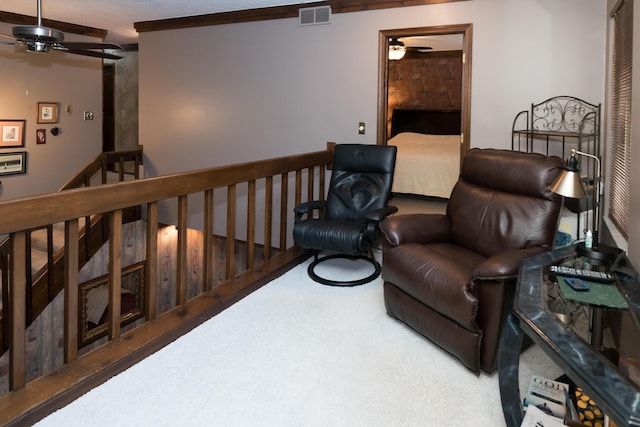 sitting room with ceiling fan, carpet, and crown molding