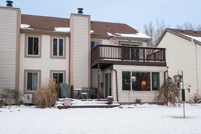 snow covered back of property with a balcony