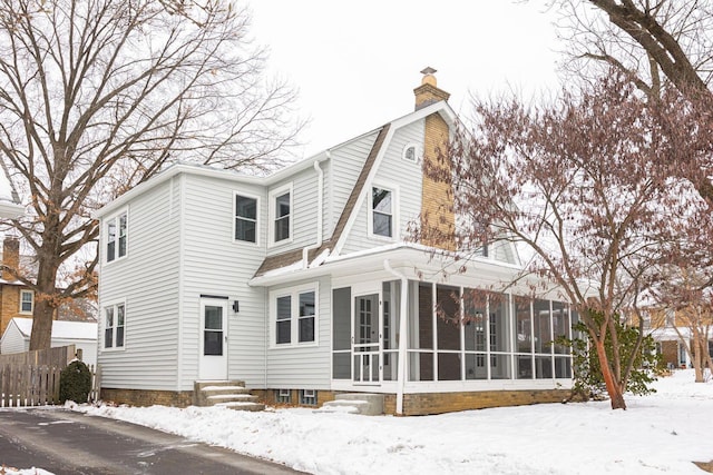 snow covered property with a sunroom