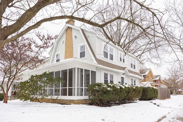 view of snowy exterior with a sunroom