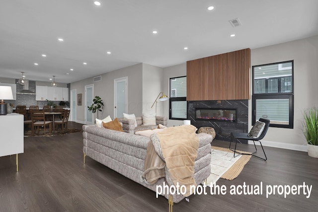 living area with recessed lighting, a large fireplace, dark wood-type flooring, visible vents, and baseboards