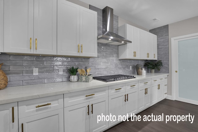 kitchen featuring stainless steel gas cooktop, white cabinetry, wall chimney range hood, decorative backsplash, and dark wood-style floors