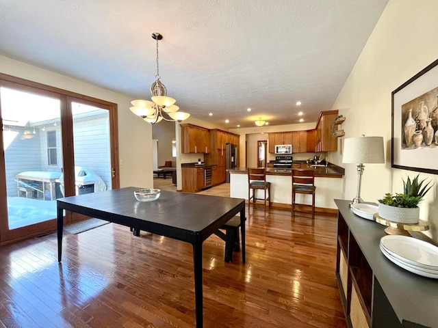 dining area with a notable chandelier, dark hardwood / wood-style floors, and a textured ceiling