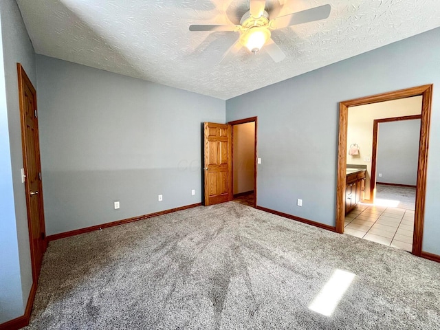 unfurnished bedroom featuring a textured ceiling, light colored carpet, ceiling fan, and ensuite bathroom