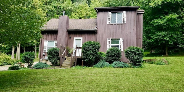 view of front of house featuring a shingled roof, a chimney, and a front yard