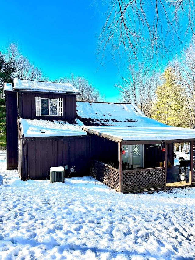 snow covered rear of property with covered porch