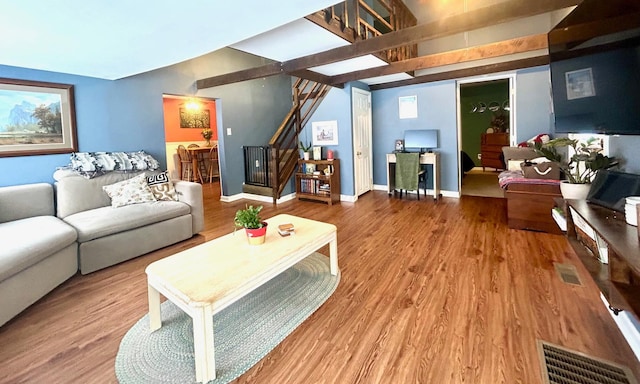 living area featuring stairway, wood finished floors, visible vents, and baseboards