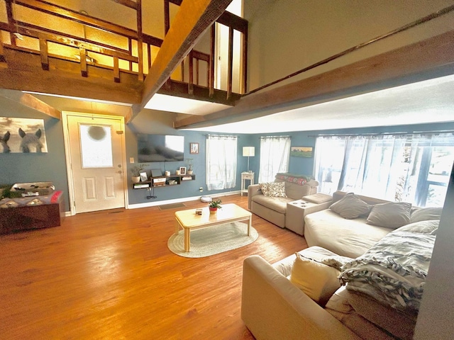 living room featuring a high ceiling, wood finished floors, and baseboards