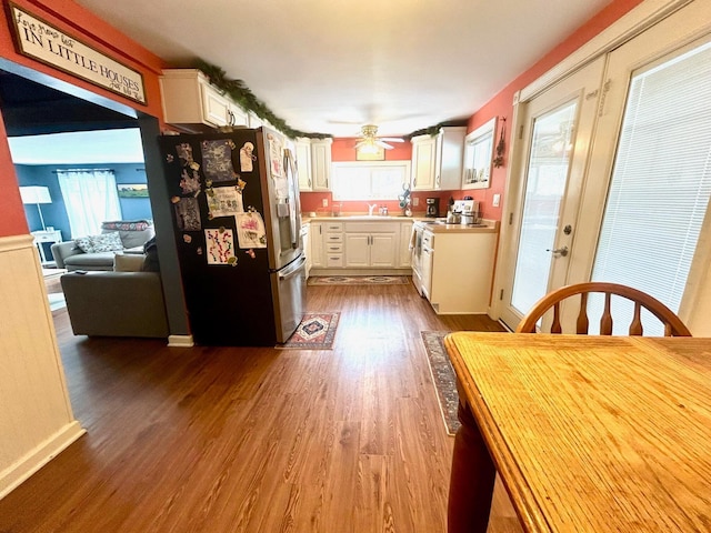 kitchen with dark wood finished floors, light countertops, white cabinetry, stainless steel fridge, and plenty of natural light