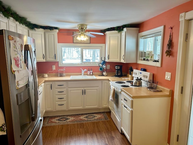 kitchen featuring white range with electric stovetop, dark wood-style flooring, light countertops, a sink, and stainless steel fridge