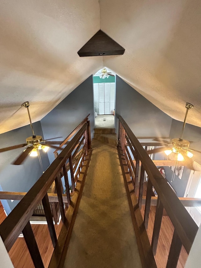 hall featuring vaulted ceiling, dark wood-type flooring, and an upstairs landing