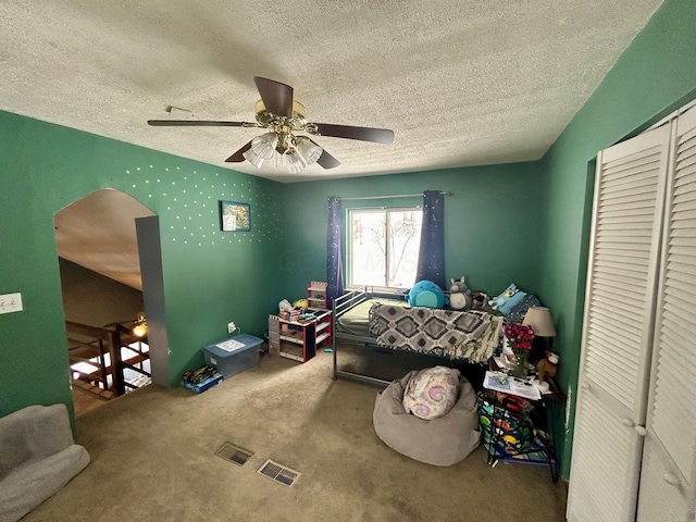 bedroom with arched walkways, a closet, carpet flooring, and a textured ceiling