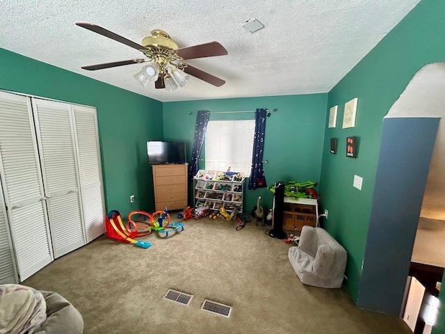 playroom featuring a textured ceiling, carpet flooring, and a ceiling fan