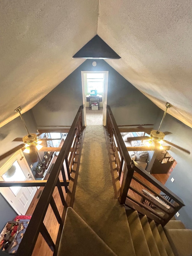 stairs featuring carpet floors, vaulted ceiling, a textured ceiling, and a ceiling fan