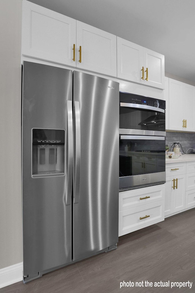 kitchen with dark hardwood / wood-style floors, decorative backsplash, white cabinetry, and stainless steel appliances