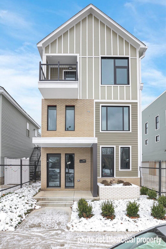 snow covered rear of property with a balcony